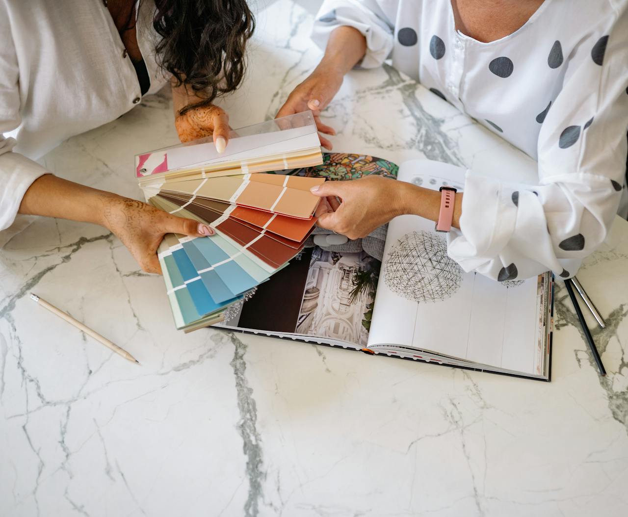 about-us Two women in an office collaborating on color palettes for interior design planning.